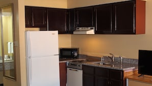 Una cocina con armarios de madera oscura, un refrigerador blanco, un microondas, una estufa y un lavamanos.