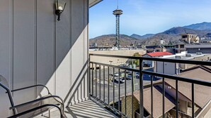 A balcony with a view of a tower, parking lot, and mountains.