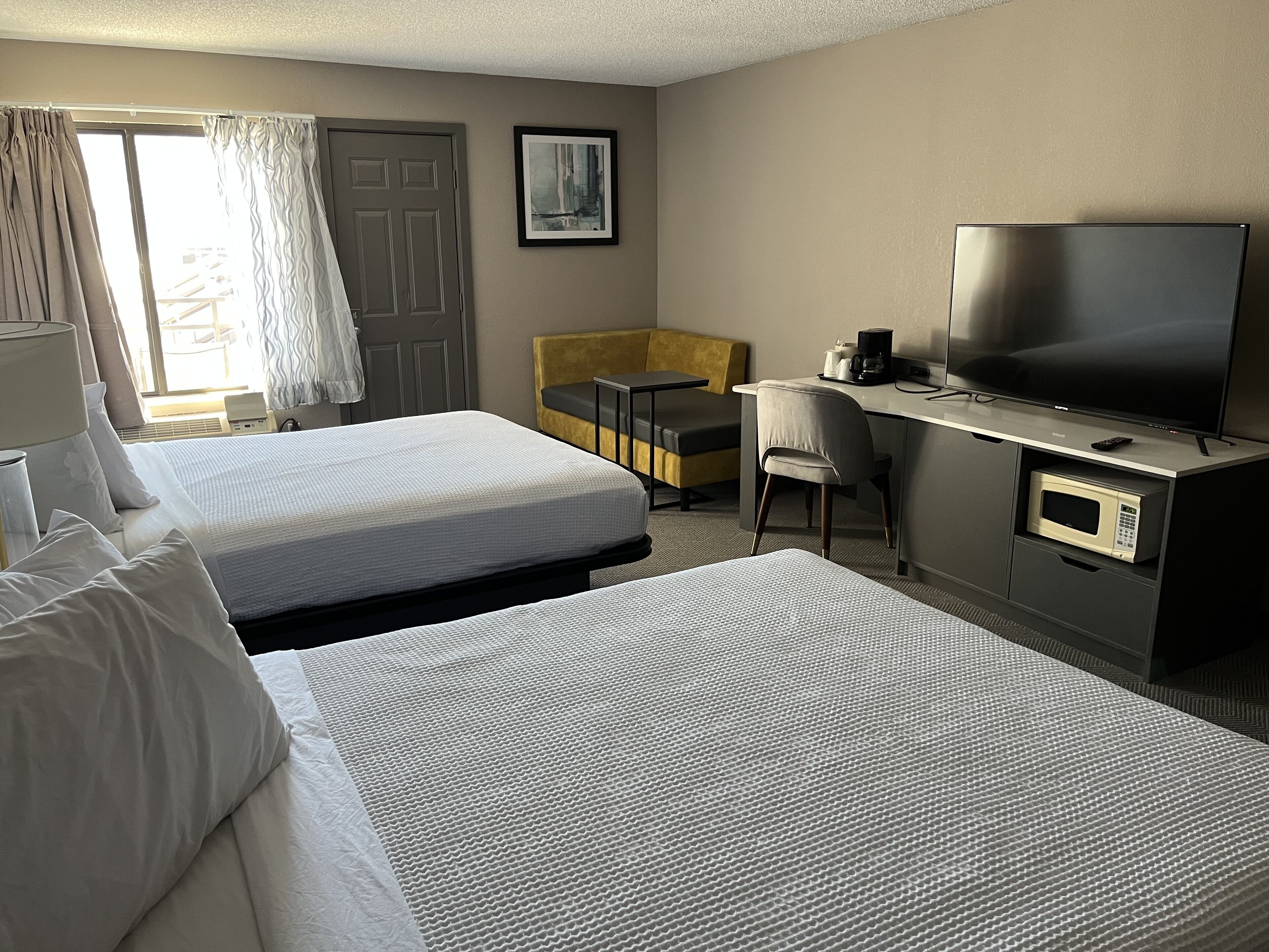 Een hotelkamer met twee bedden, een bureau met een televisie, een magnetron en een stoel.
