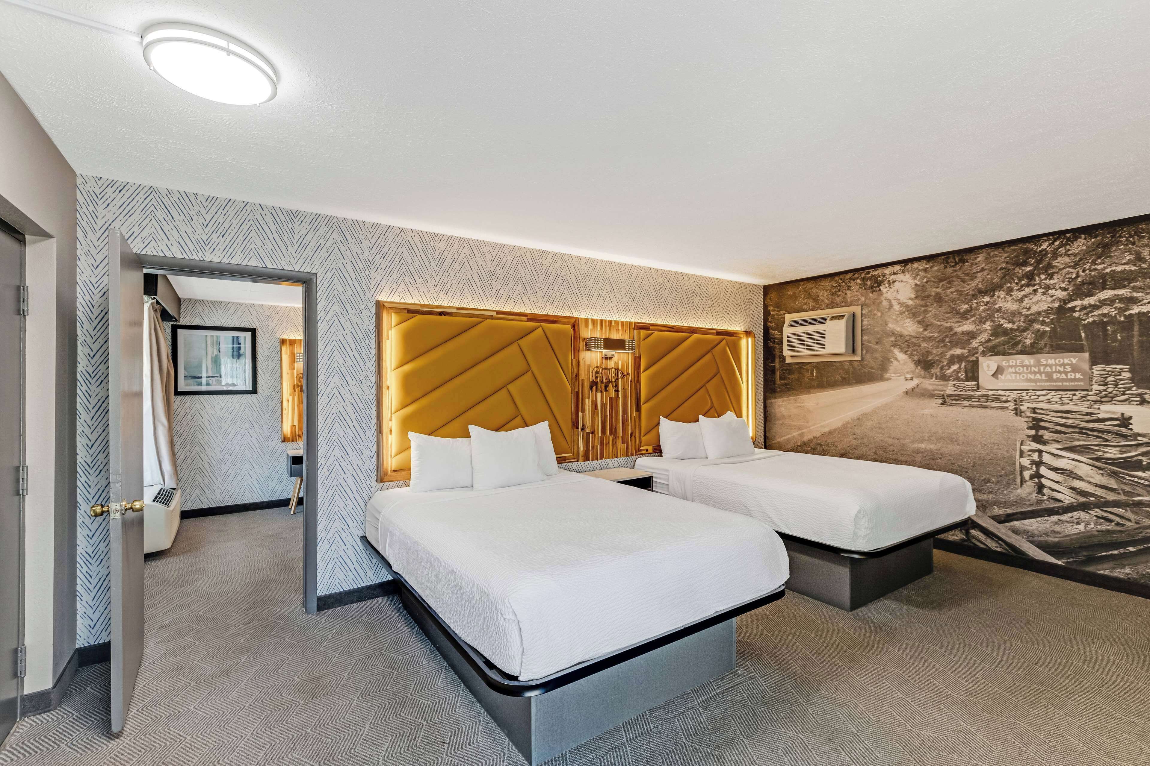 A hotel room with two beds, a large wall mural, and a modern headboard.
