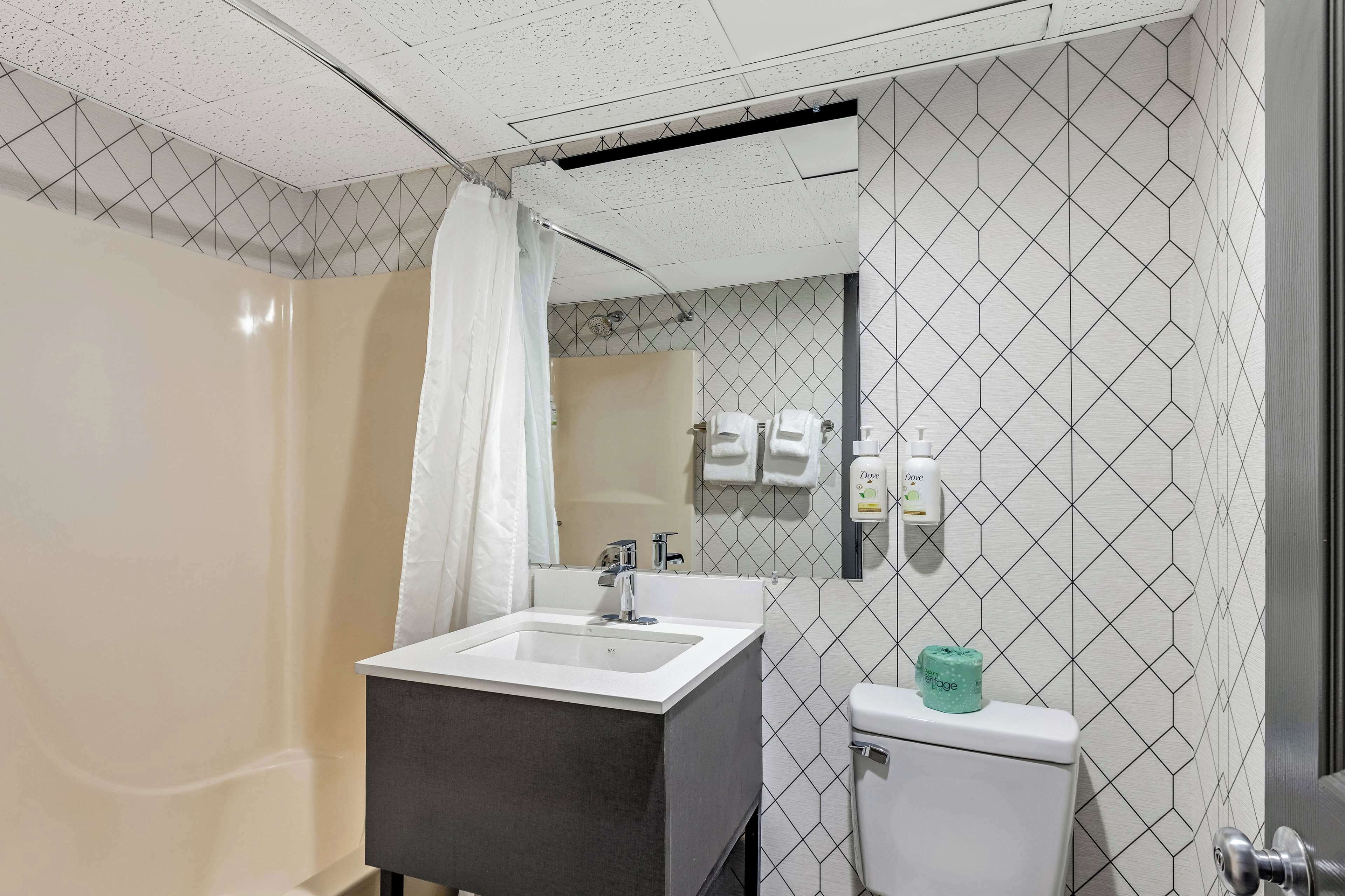 A bathroom with a white sink, a mirror, a toilet, and a shower curtain.