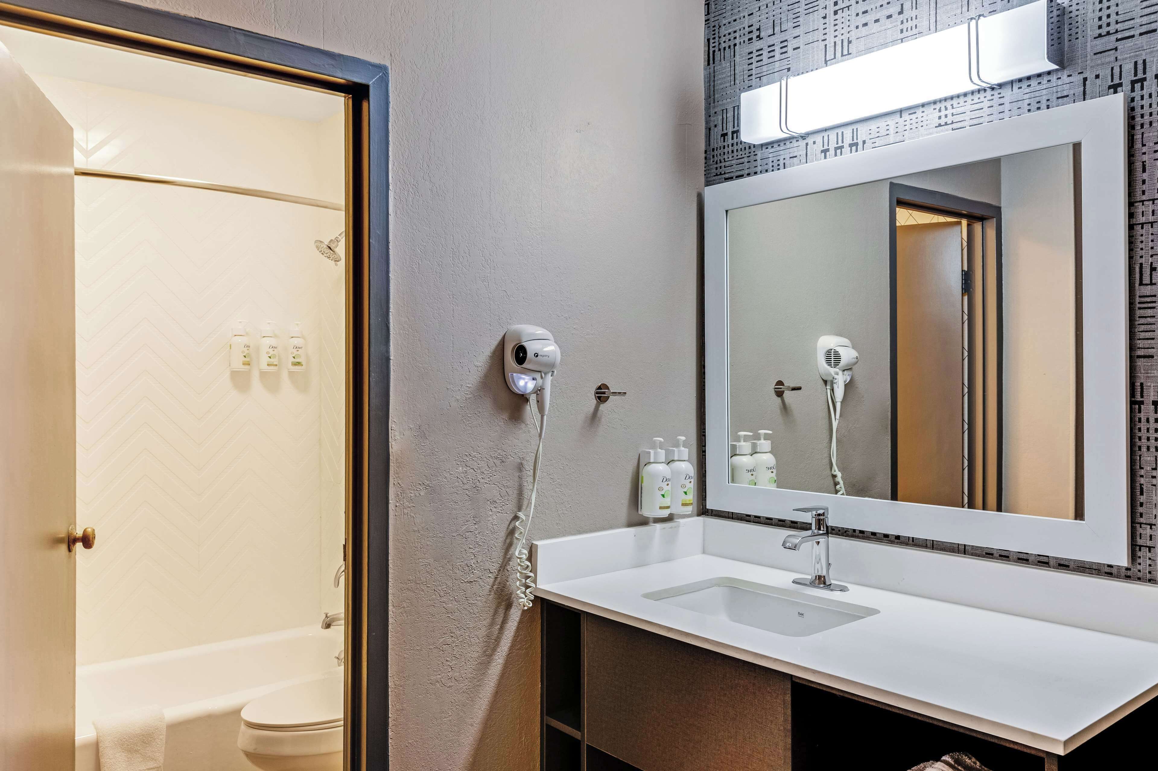 A modern bathroom with a white sink, a large mirror, and a shower.