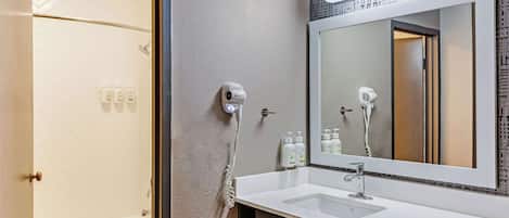 Un baño moderno con un lavabo blanco, un espejo grande y una ducha.