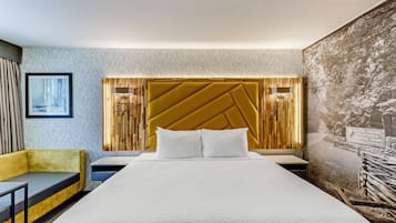 Ein Hotelzimmer mit einem großen Bett, einem gelben Sofa, einem gerahmten Bild an der Wand und einem Poster vom Great Smoky Mountains National Park.