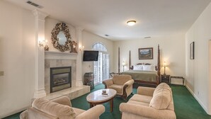 A hotel room with a fireplace, a bed, a television, and a view of the outdoors. - 5th Street Inn (Mariposa)