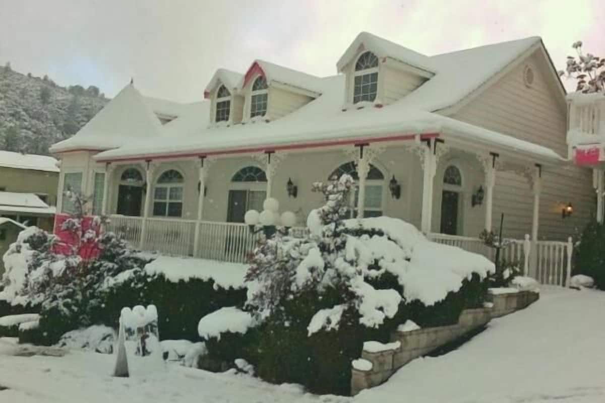 A two-story house with a snow-covered roof and a porch.