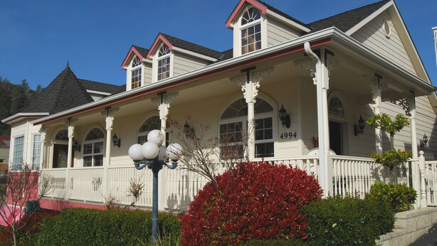 A two-story house with a porch, arched windows, and a chimney. - 5th Street Inn (Mariposa)