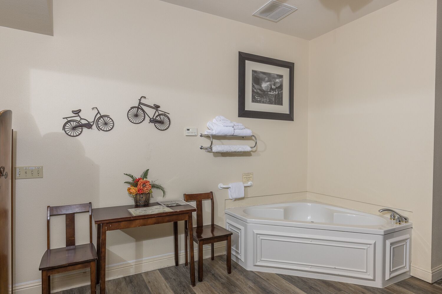 Un bagno con una vasca, un tavolino con sedie, una decorazione a bicicletta appesa al muro e un quadro incorniciato.