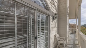 A covered porch with a railing, a bench, and a wall-mounted light fixture. - 5th Street Inn (Mariposa)