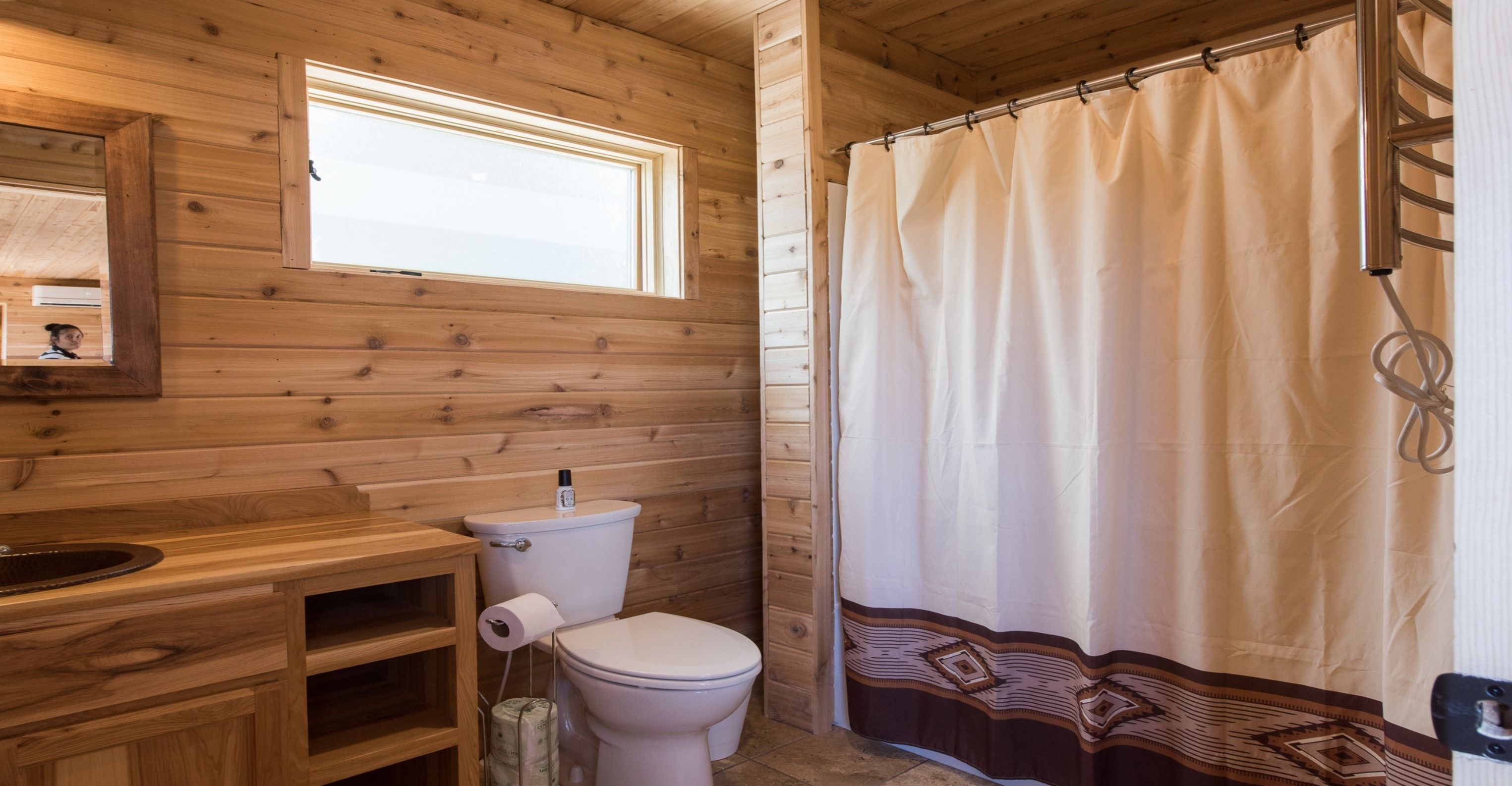 Een houten badkamer met een toilet, wastafel en douchegordijn.
