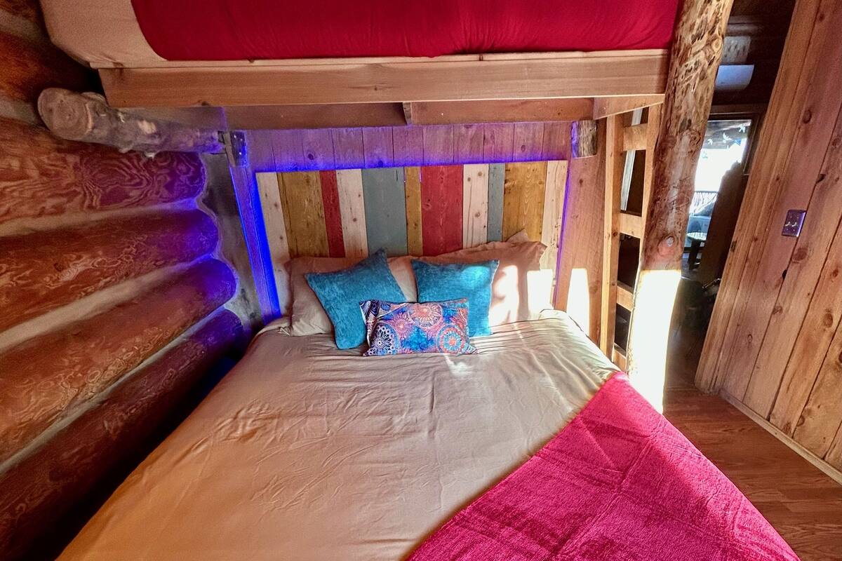 A wooden cabin-style bedroom with a bed, pillows, and a blanket.