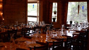 A restaurant with multiple dining tables set for guests, featuring wooden interiors and string lights. - Boulder Mountain Guest Ranch (Boulder)