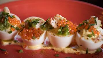 A dish with poached eggs, caviar, and herbs on a red plate.