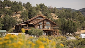 A large log cabin with a balcony, surrounded by natural landscape and trees. - Boulder Mountain Guest Ranch (Boulder)
