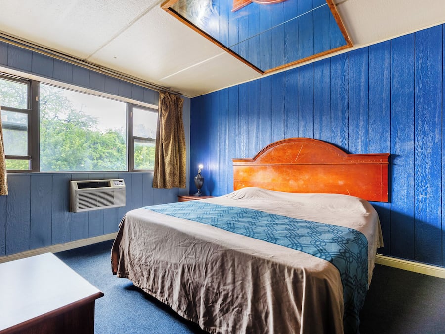 Ein Zimmer mit einem Bett, einem Schreibtisch und einem Vorhangfenster.