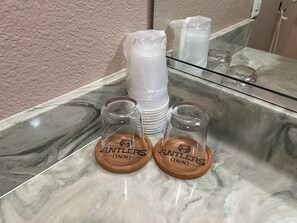 A bathroom counter with two coasters labeled "Antlers Inn" and a stack of plastic bottles.