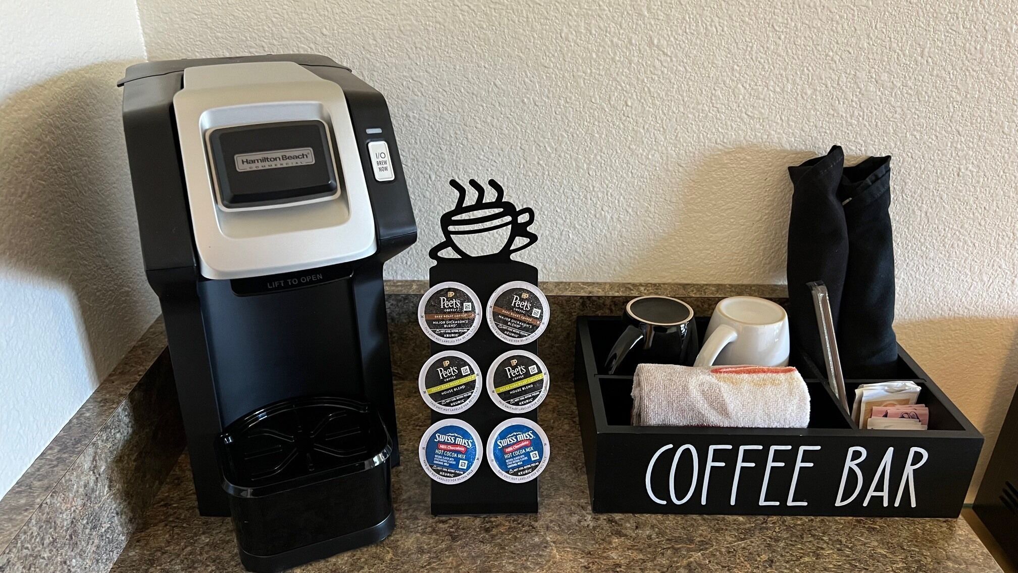 A coffee station with a Hamilton Beach commercial coffee maker, Peet's Coffee pods, and a coffee bar sign.