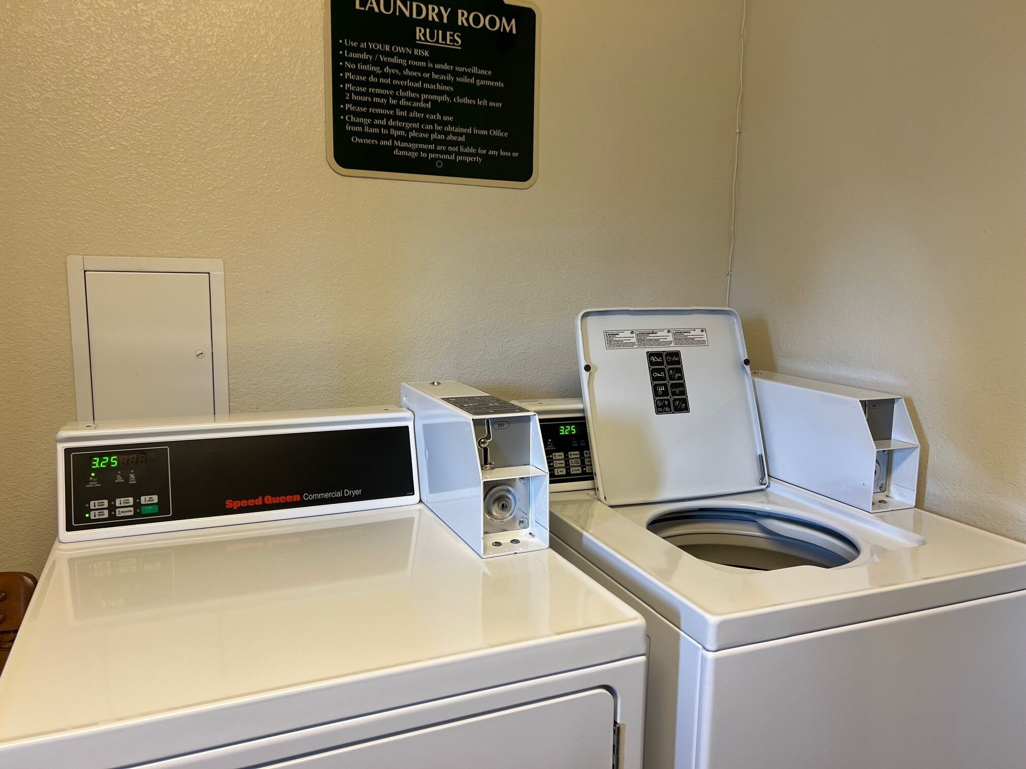 A laundry room with two Speed Queen Commercial Dryers and a sign detailing laundry room rules.