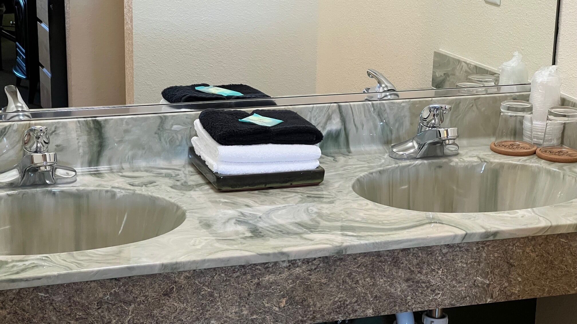 Un baño con dos lavamanos, un espejo y un perchero con toallas dobladas.