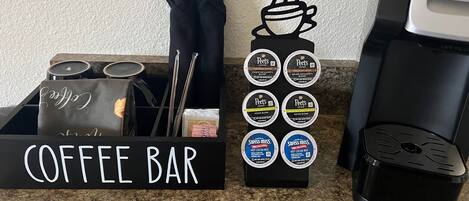 Un espacio de cafetería con una máquina de café, un preparador de café y una presentación de cápsulas de café.