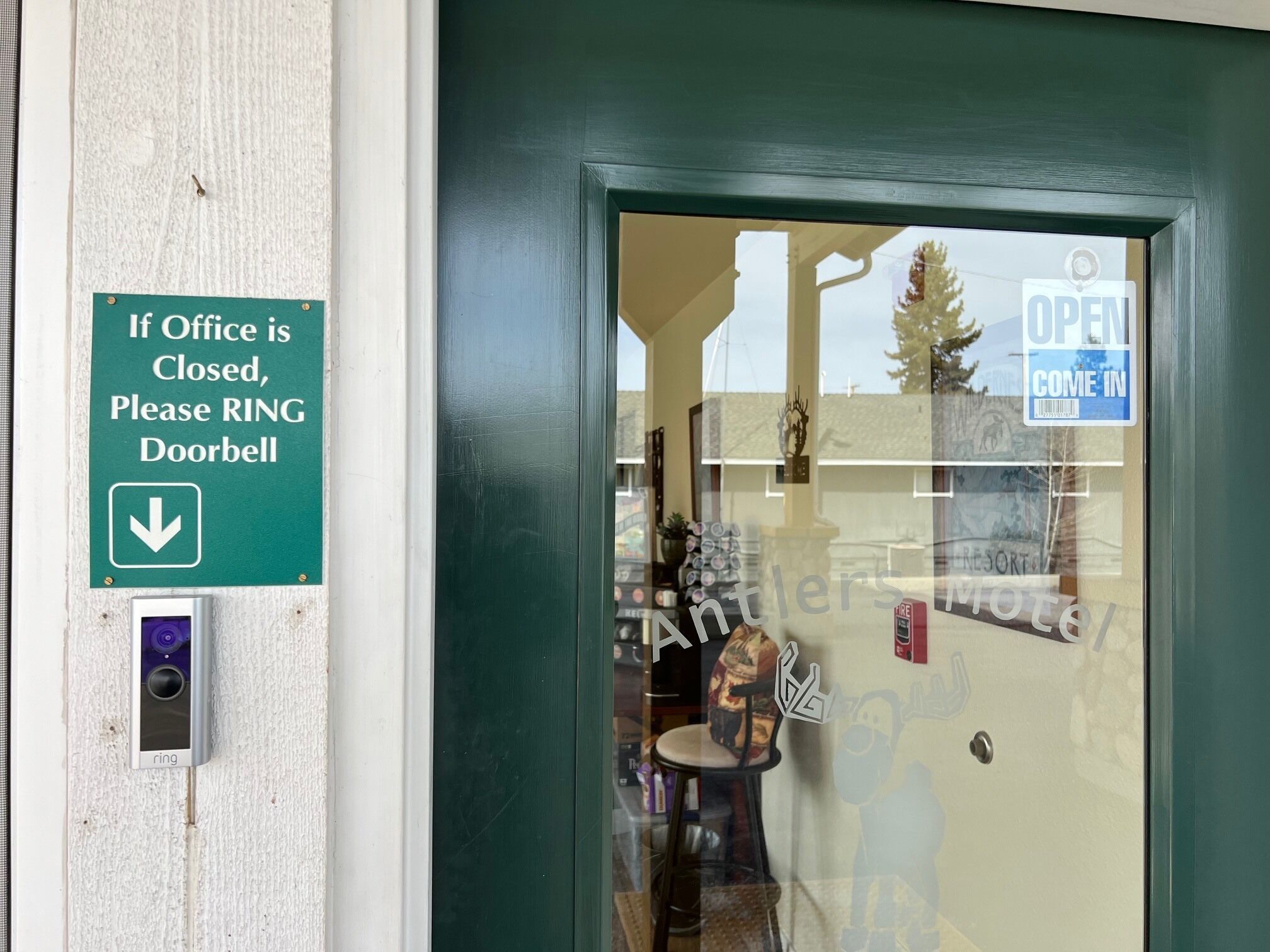 Una puerta con un cartel que indica que se debe timbrar el timbre si la oficina está cerrada.