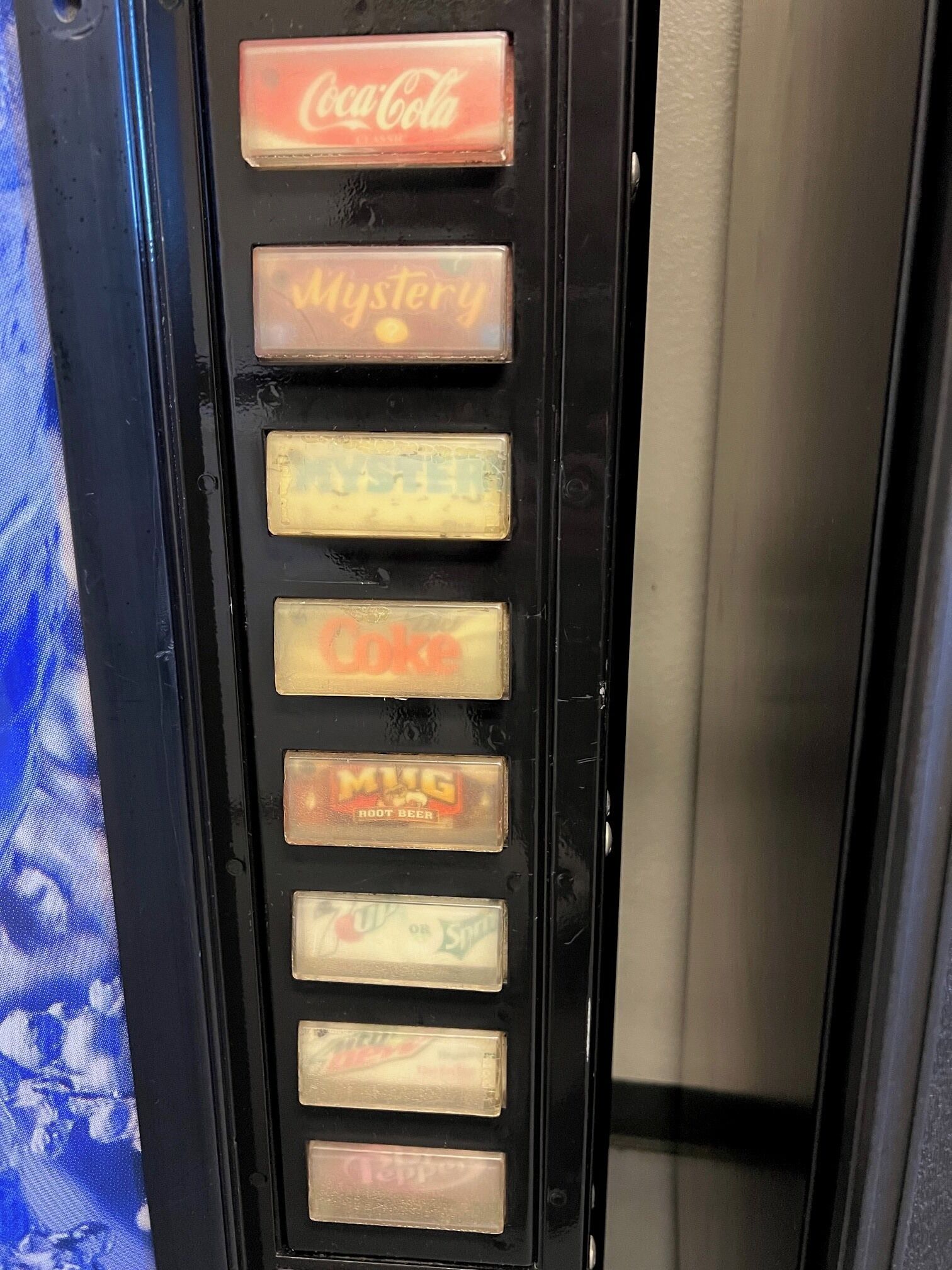 Ein Getränkeautomat mit verschiedenen Auswahlmöglichkeiten, darunter Coca-Cola, Mystery und Sprite.