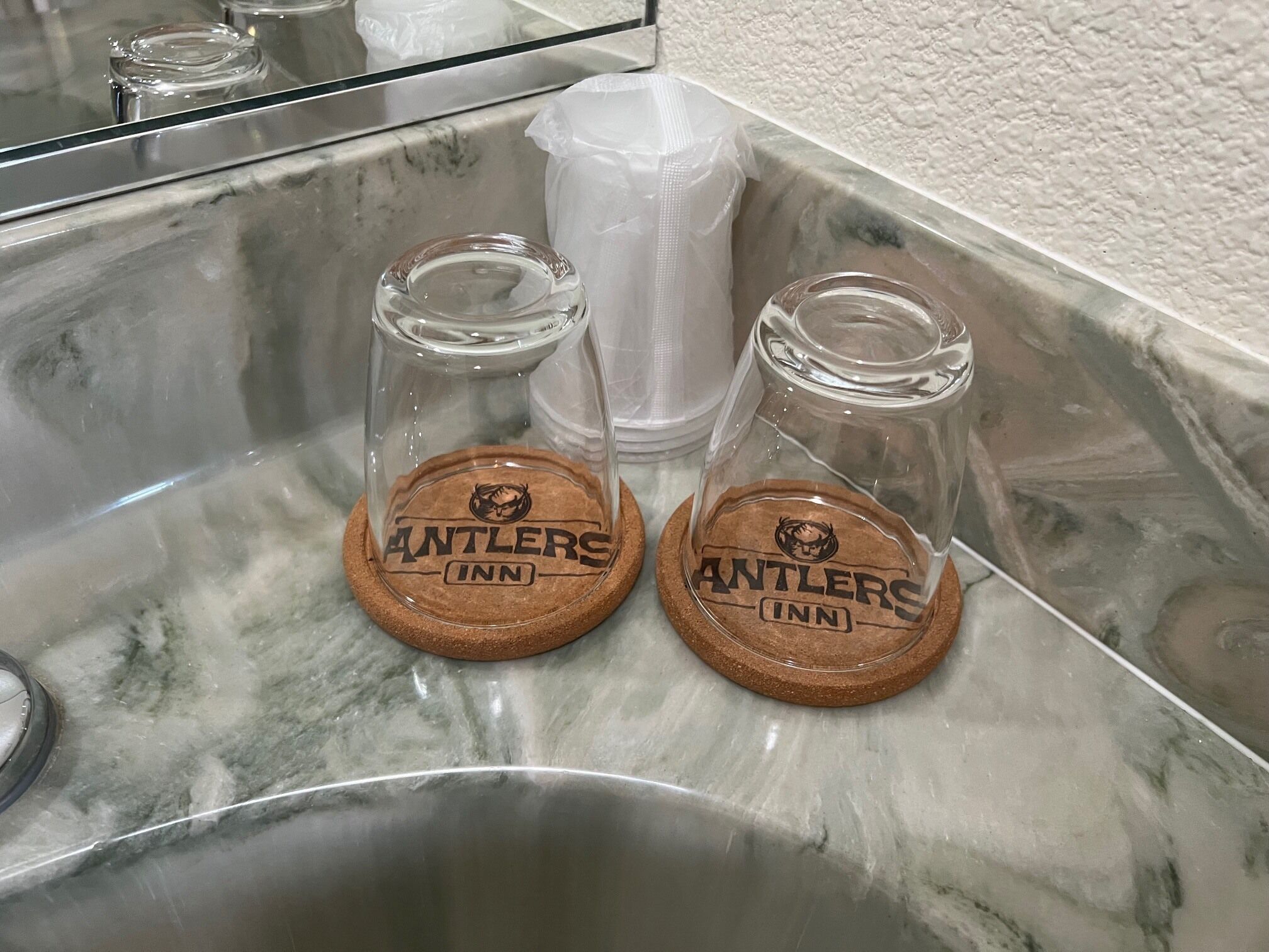 Dos botellas de vidrio con tapones de corcho sobre una encimera de mármol.