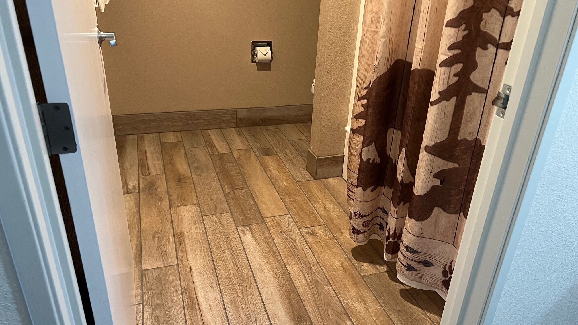 A hallway with wooden flooring, a towel rack, and a door with a handle.