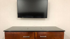 Un meuble en bois doté de deux portes et d’une surface plane sur le dessus, placé contre un mur, avec un téléviseur fixé au-dessus.