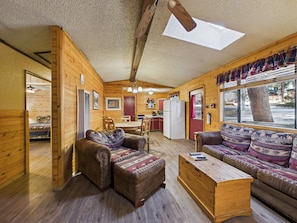L’intérieur d’une cabane en rondins comprend un coin repas, une cuisine et une grande fenêtre offrant une vue panoramique.