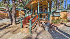 A rustic cabin with a porch, steps, and a sign indicating parking. - Whispering Pine Cabins (Ruidoso)