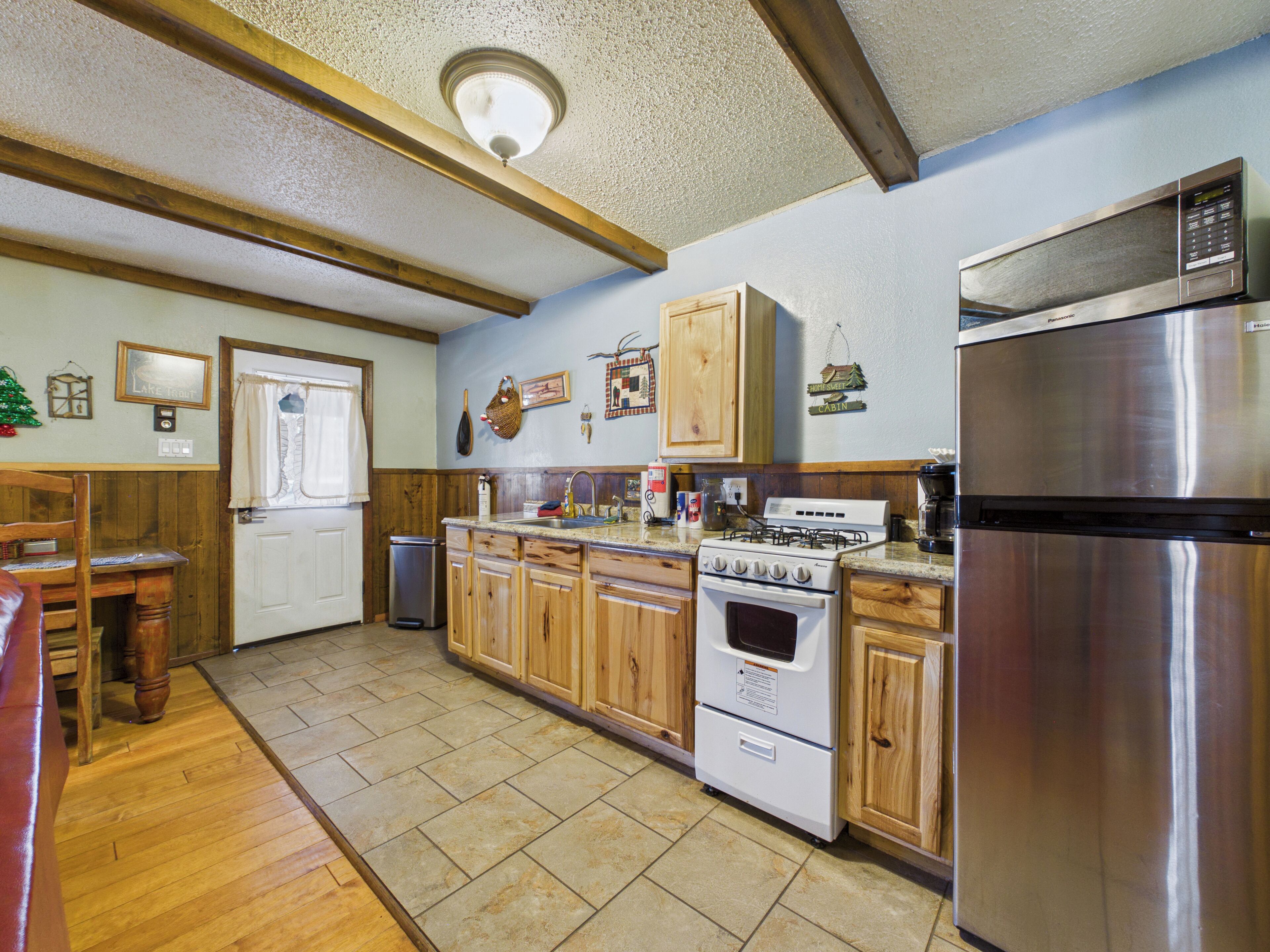 Una cocina con armarios de madera, estufa, refrigerador y pileta.