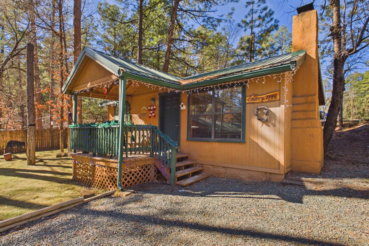Une cabane en bois avec une véranda, une cheminée et une enseigne sur laquelle on peut lire « Cherry Tree ».