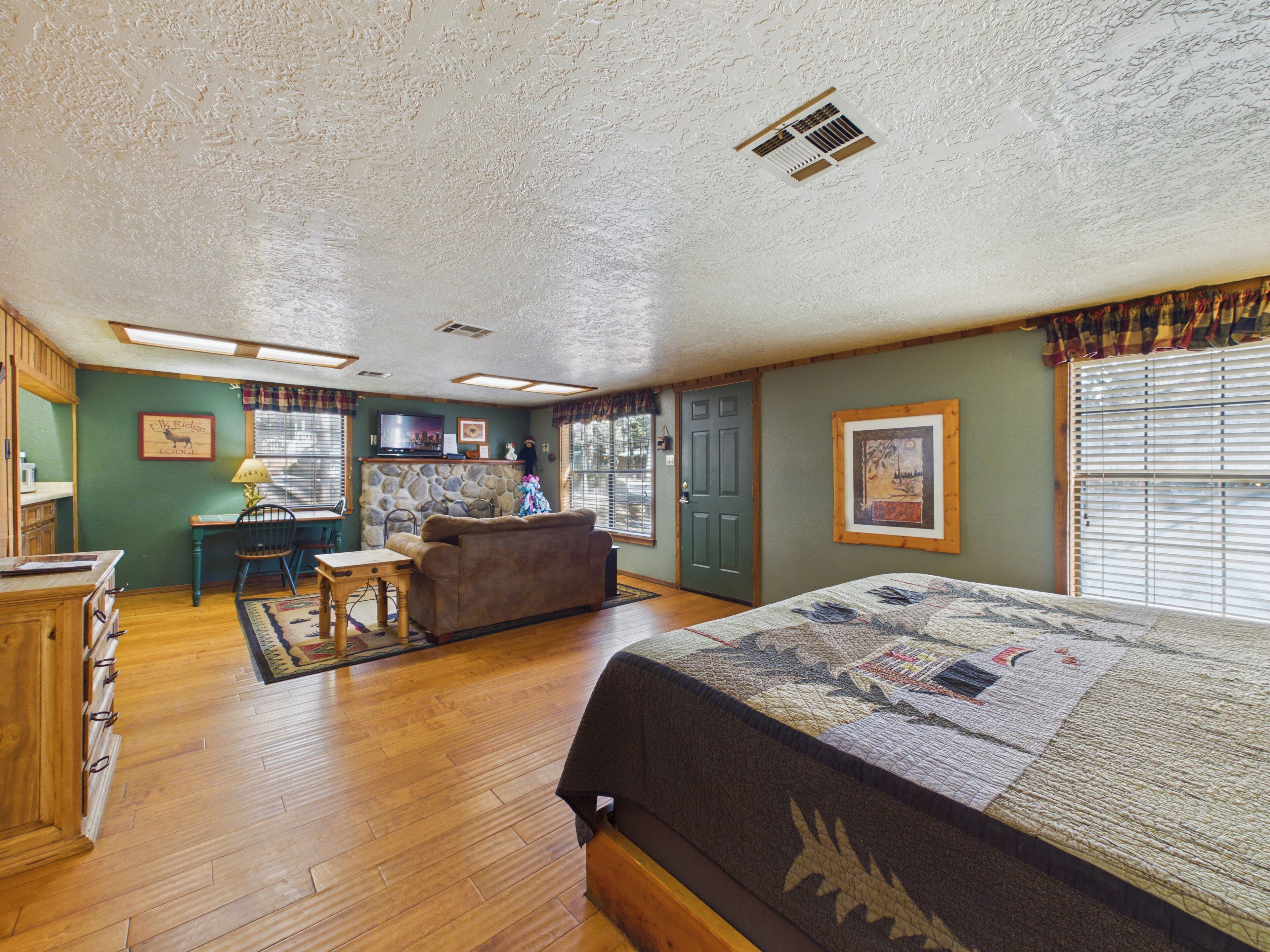 A room with a bed, a desk, a chair, a fireplace, and a window.