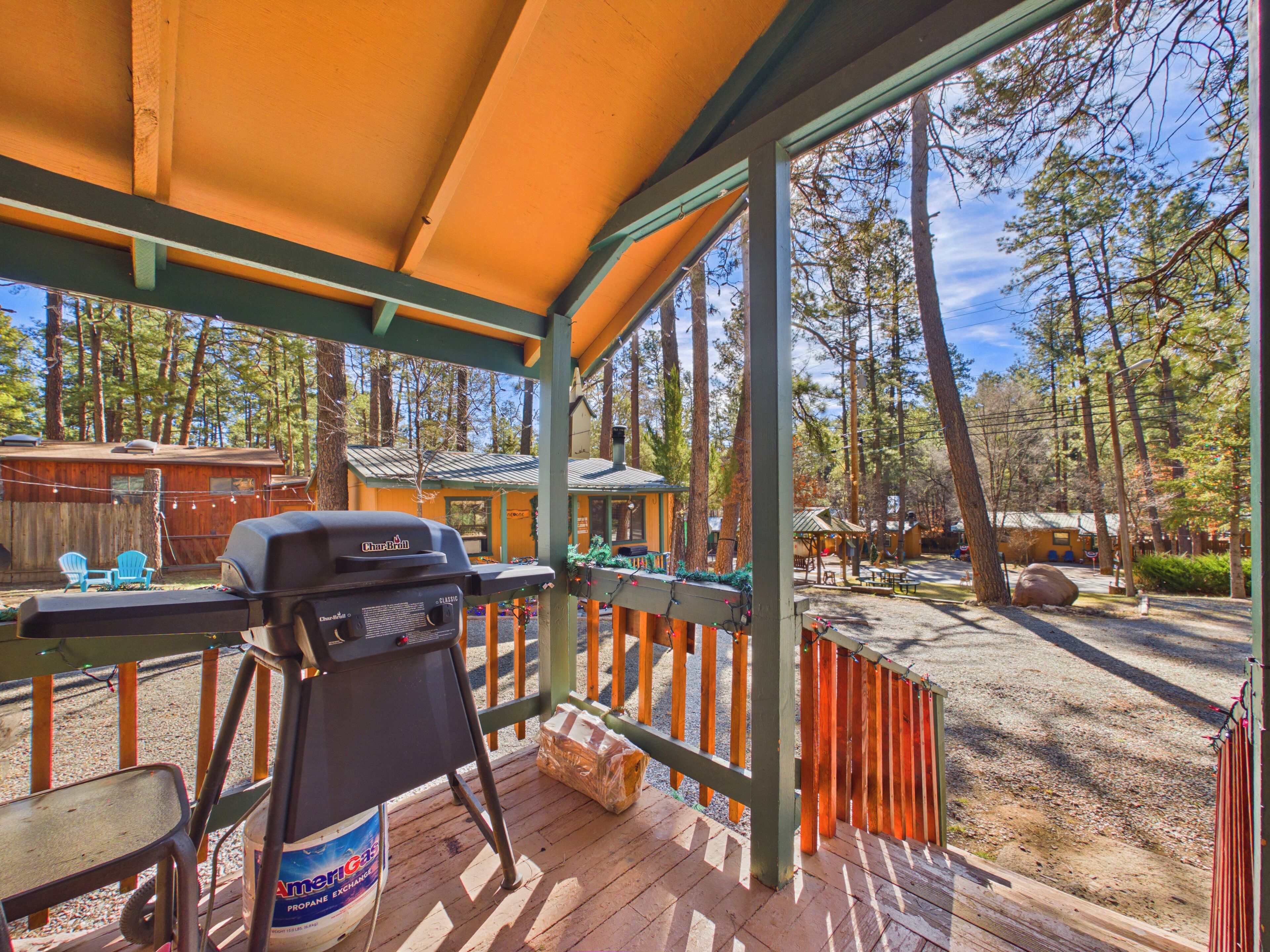 A covered outdoor area with a grill, chairs, and a wooden deck.
