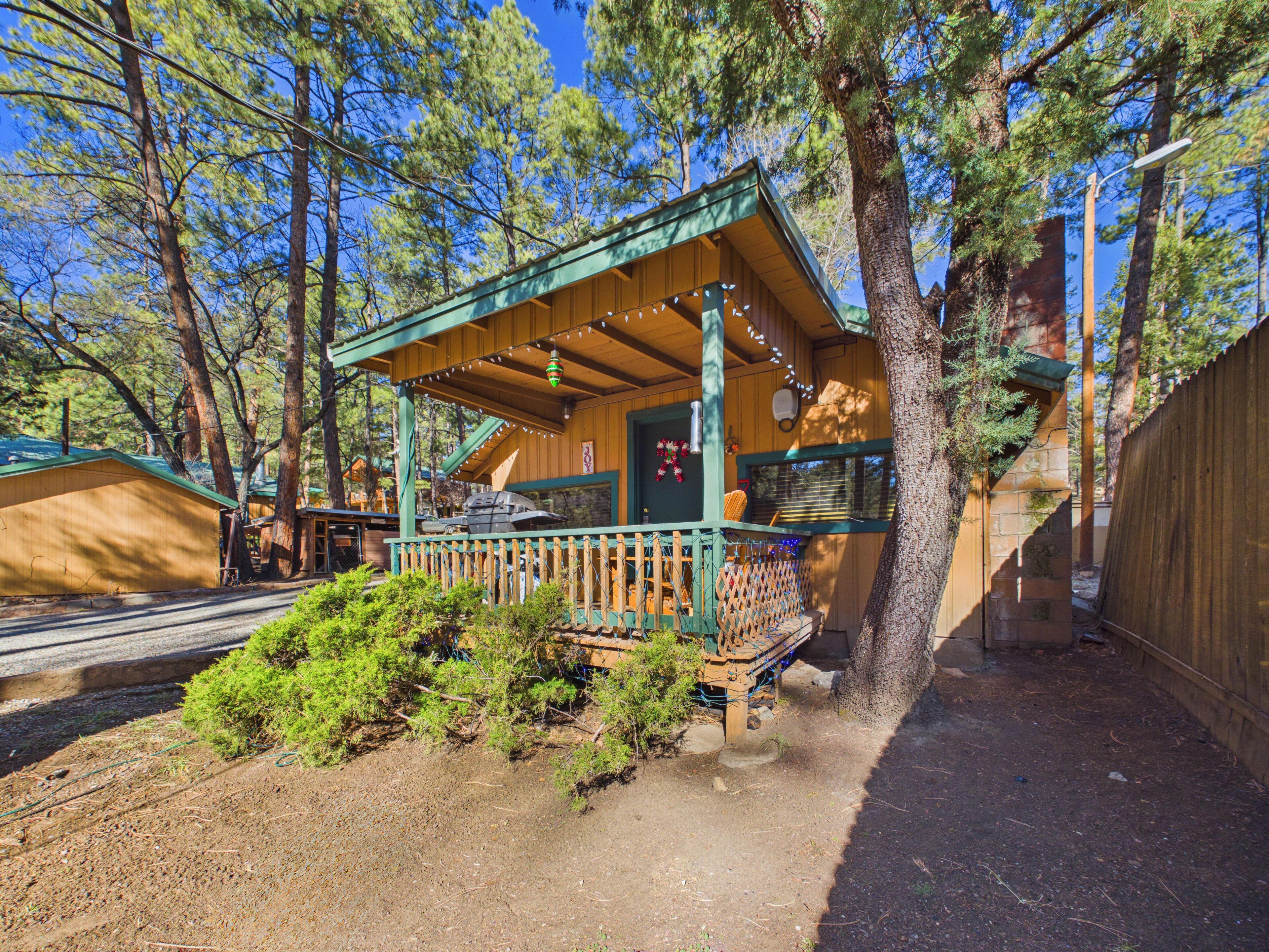 A wooden cabin with a porch, surrounded by trees.