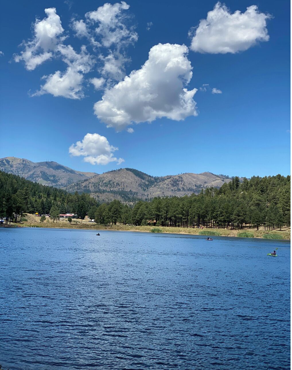 A lake with mountains in the background, clear sky, and a few boats.