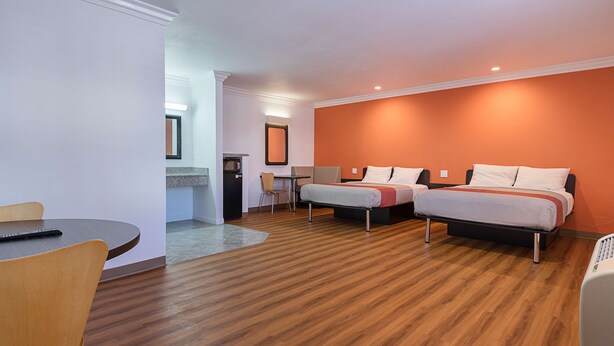Een hotelkamer met twee bedden, een bureau, een stoel en een magnetron.
