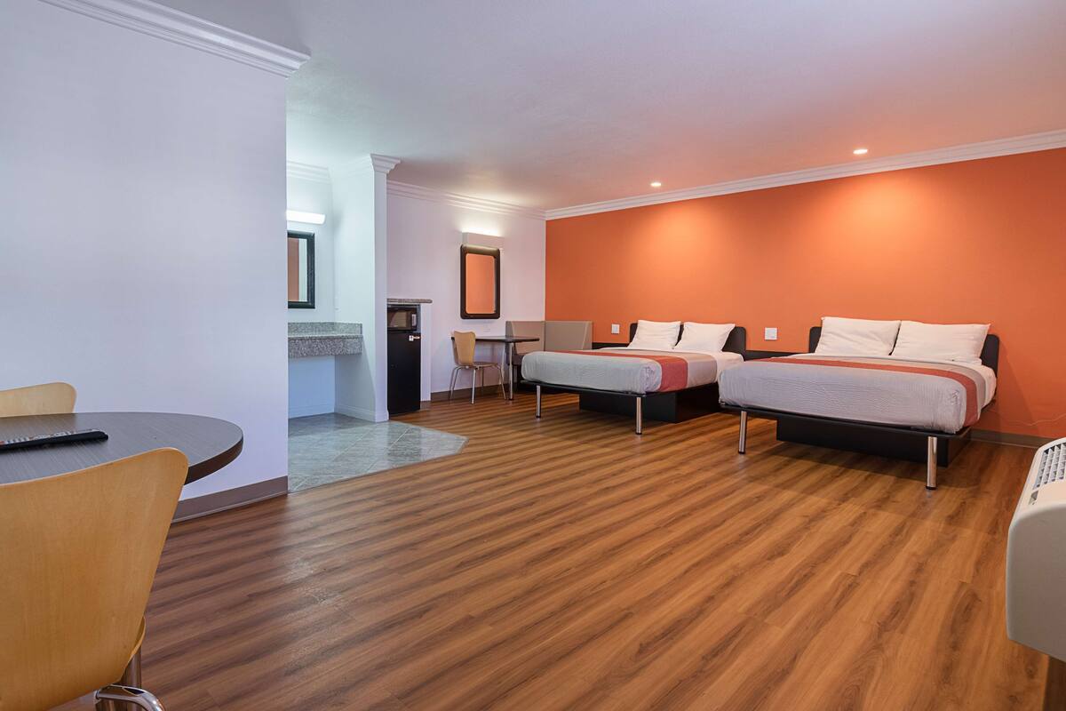 Une chambre d’hôtel avec deux lits, un bureau, une chaise et un four à micro-ondes.