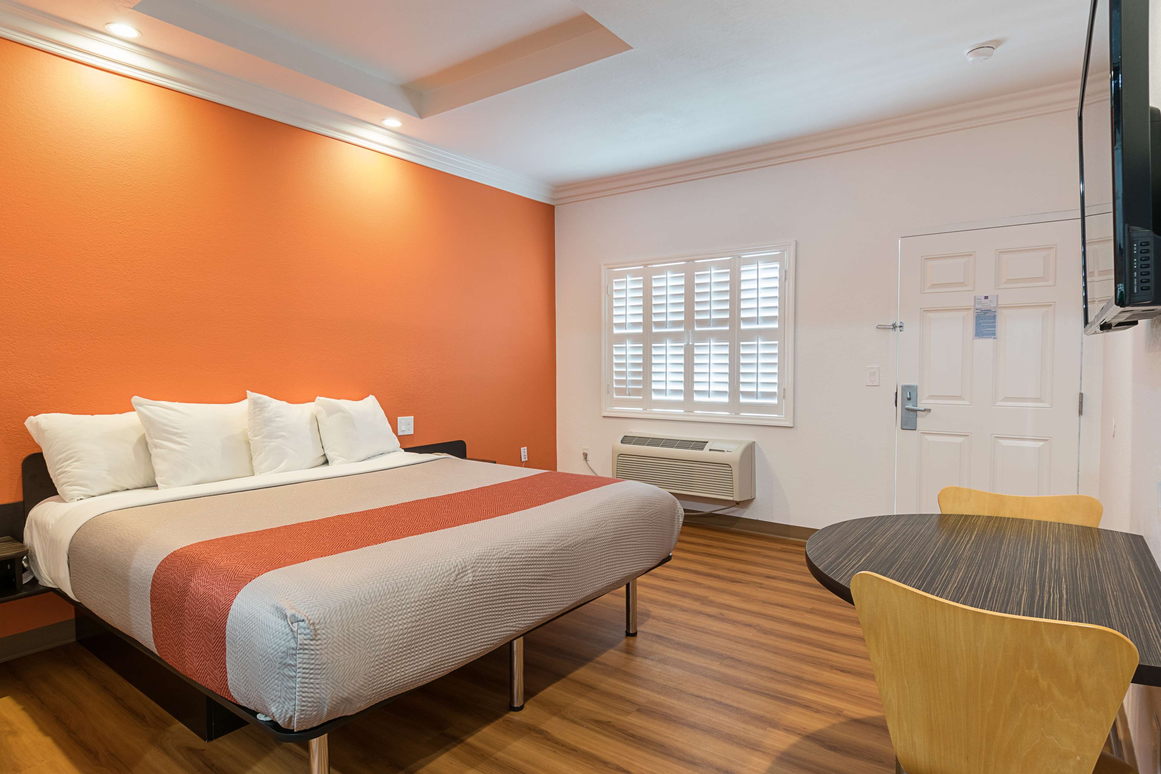 Una habitación de hotel con una cama, una mesita pequeña y un televisor.