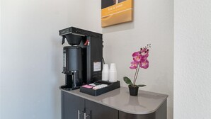 Een koffieapparaat op een aanrecht met een potorkidee.