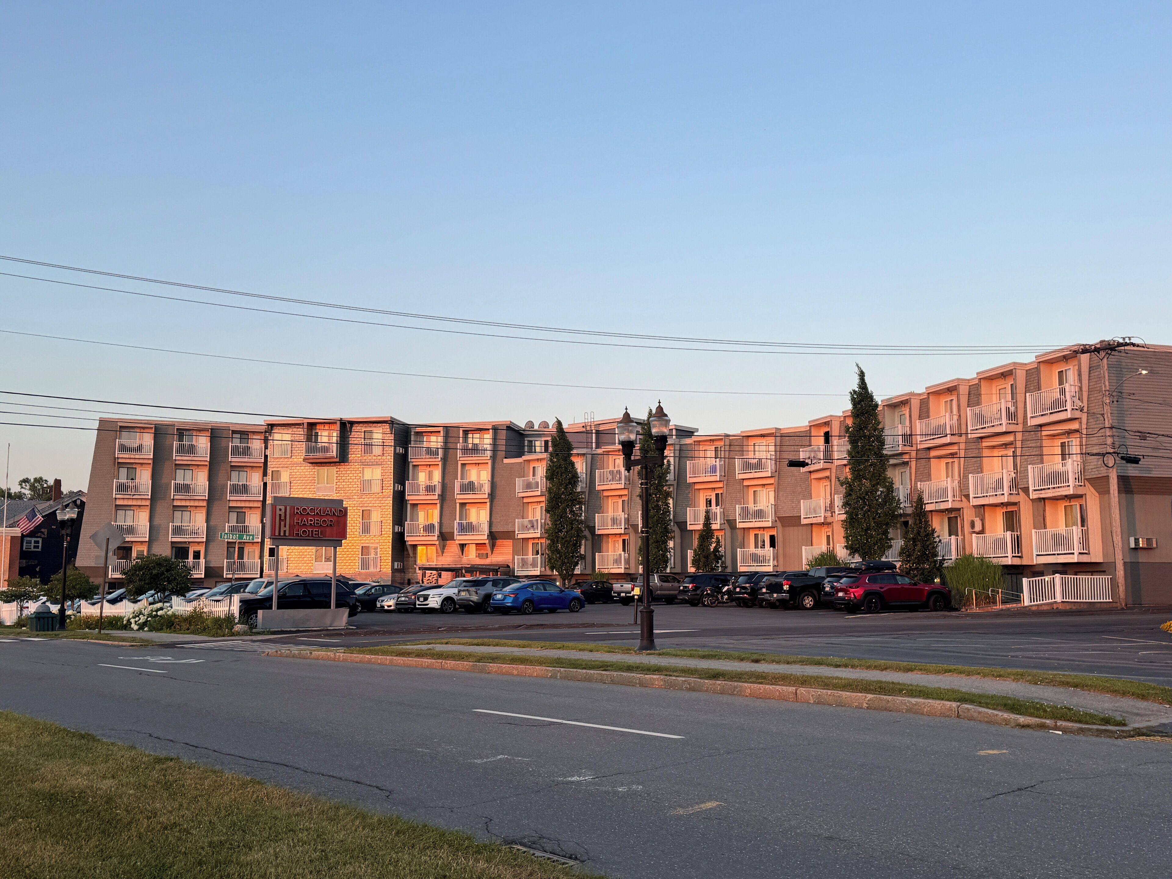 A multi-story hotel with balconies, a parking lot, and a street view.
