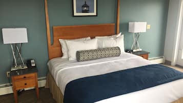 A hotel room with a large bed, two bedside tables, a nightstand, a framed picture on the wall, and a window.