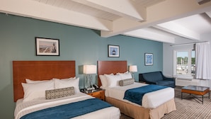 A hotel room with two beds, a sofa, a table, and a window with a view of boats. - Rockland Harbor Hotel (Rockland)