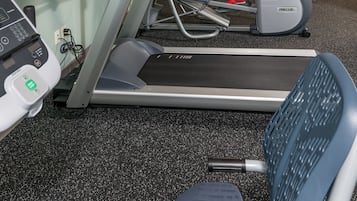 A gym with treadmills, weight benches, and a person exercising.