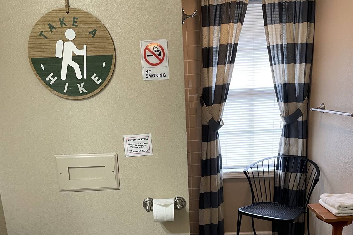 Bany amb vàter, barana, cadira, paraigua de tovalloles i cartell que indica prohibició de fumar.
