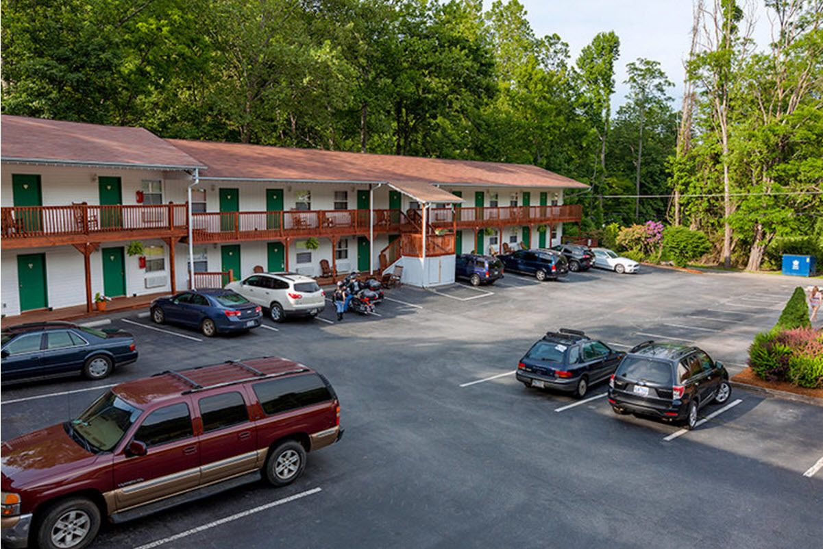 A motel with multiple rooms, a parking lot, and a small garden area.