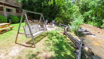 A backyard with a swing set, picnic table, and fire pit.