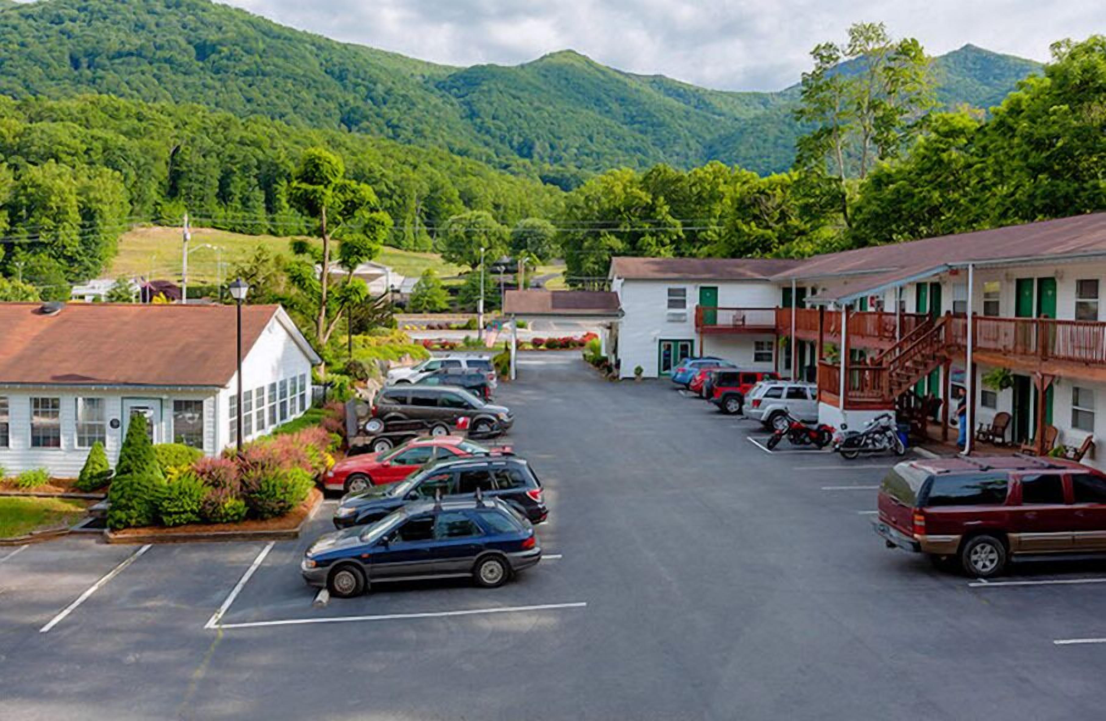 A parking lot with several cars and a building with a balcony.