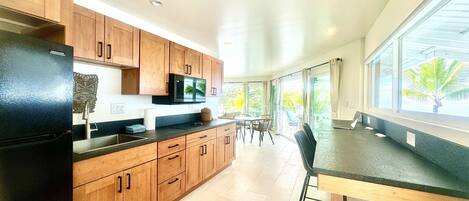 A modern kitchen with wooden cabinets, a black refrigerator, and a dining area with a table and chairs.